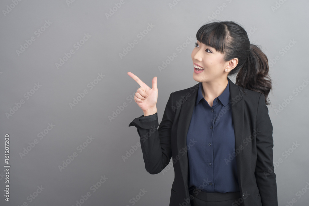 Beautiful Business Woman presenting something on grey background Beautiful Business Woman presenting something on grey background