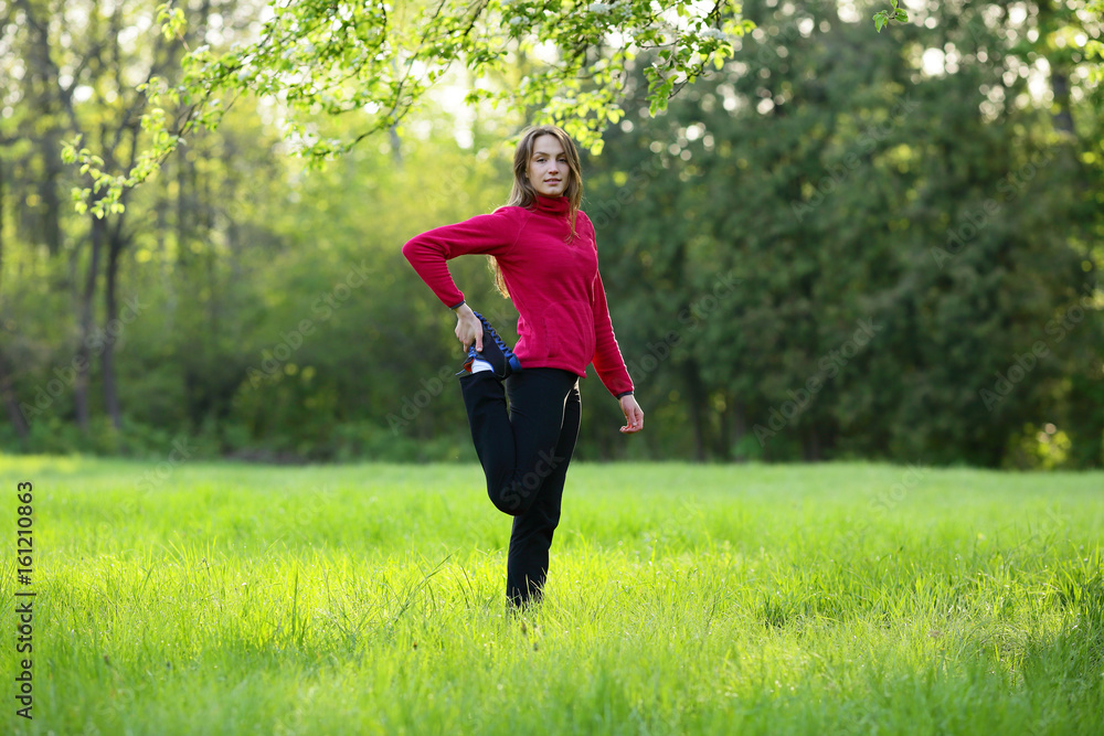 Young woman streching in green field, grass, park, morning, looking camera Young woman streching in green field, grass, park, morning, looking camera