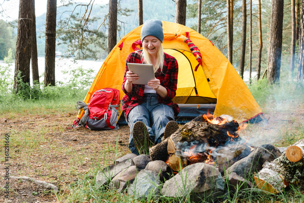 Woman using digital tablet in tent in the woods. Woman using digital tablet in tent in the woods.