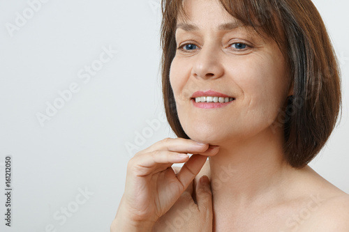 Attractive middle aged woman touching her cheek skin, mature beauty concept