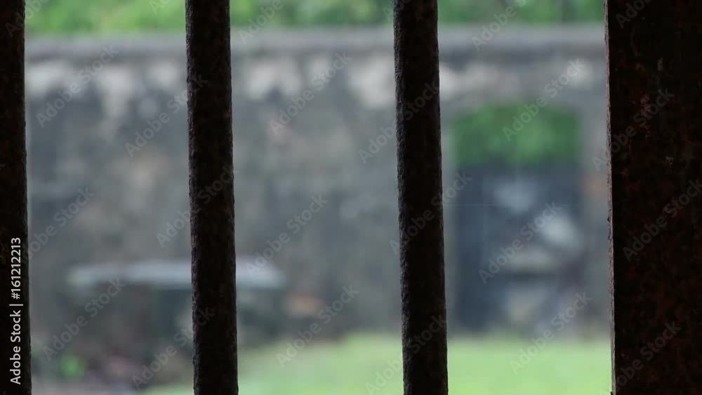Static shot looking through jail bars to the outside on Devils Island Penal Colony in French Guiana. Heavy rain is falling Static shot looking through jail bars to the outside on Devils Island Penal Colony in French Guiana. Heavy rain is falling