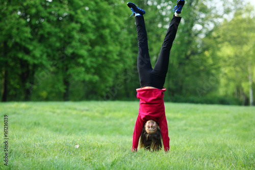 Upside down handstand happy smile sport young woman outdoor, green park, grass, full lenght