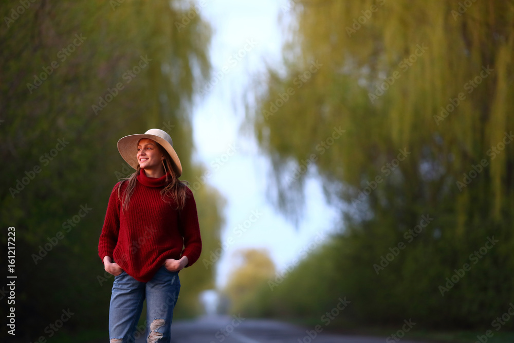 Smiling traveling woman looking away standing front on road outdoor, natural background