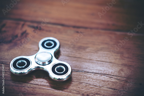 Top view image of a metal silver color fidget spinner on wooden table