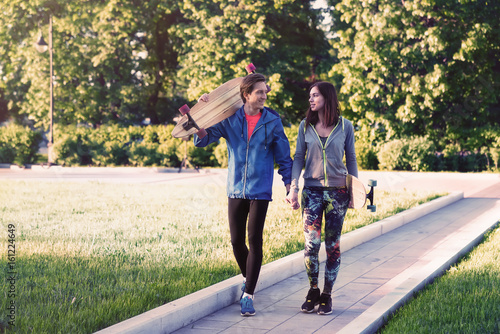 A man and a girl are walking with a skateboard in their hands