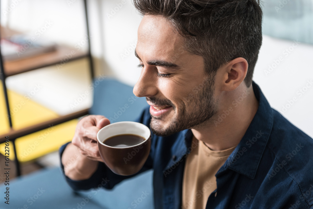 Cheerful handsome guy taking pleasure from hot drink Cheerful handsome guy taking pleasure from hot drink