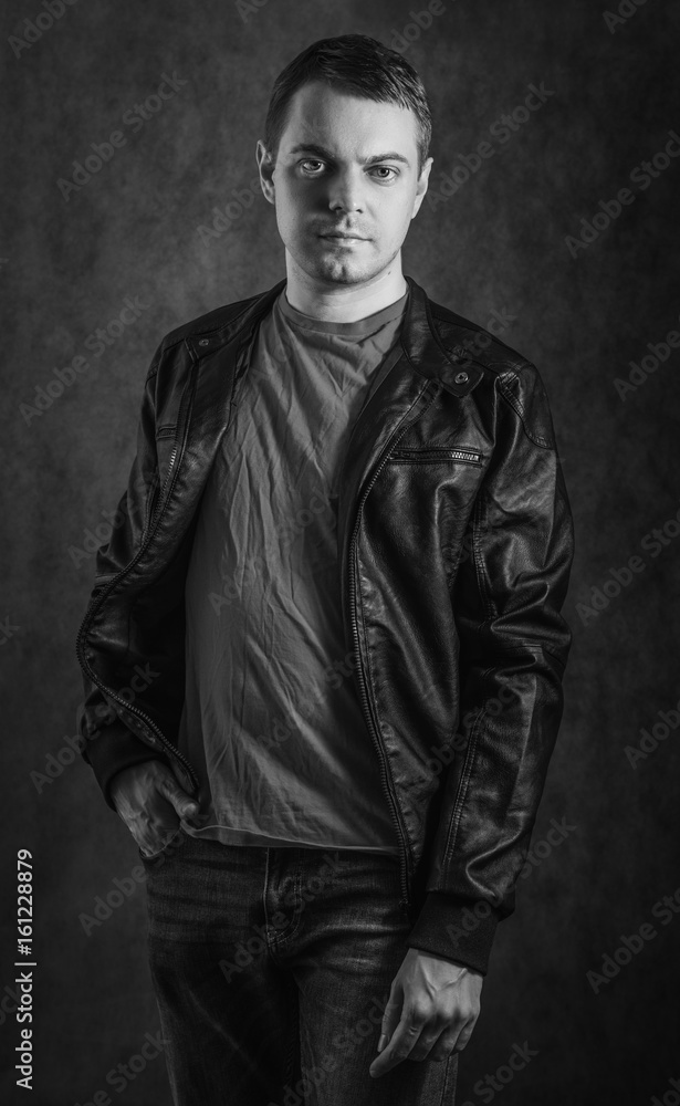 Young man in coat on dark background. Black and white toned. Young man in coat on dark background. Black and white toned.