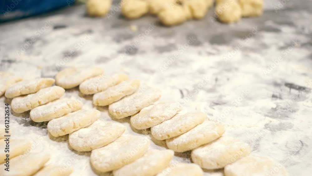 Woman rolls the dough with her hands and flops the flour Woman rolls the dough with her hands and flops the flour