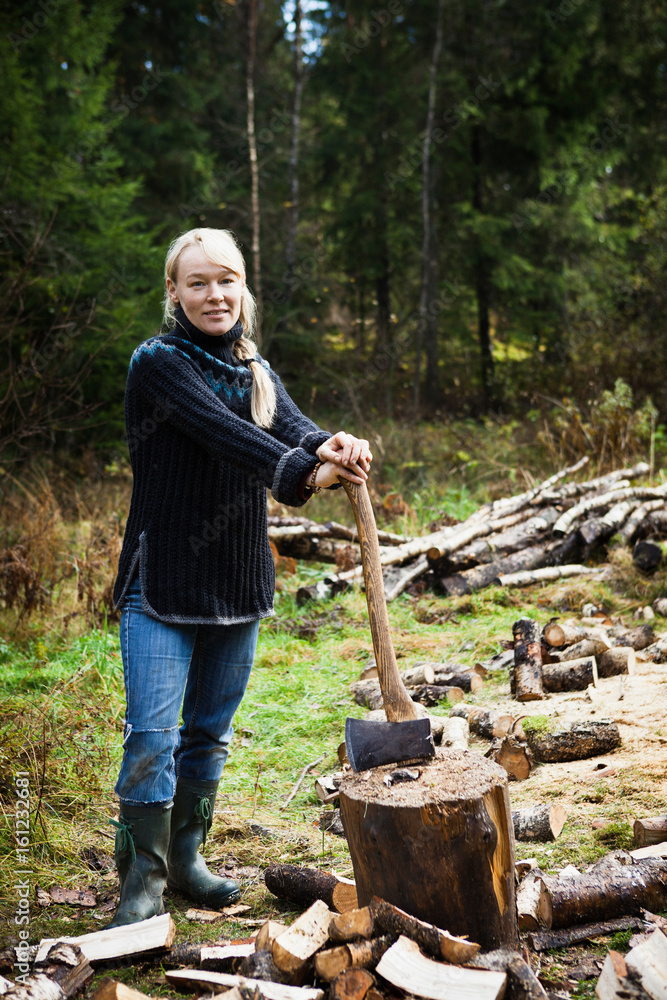 Woman chopping firewood in forest Woman chopping firewood in forest