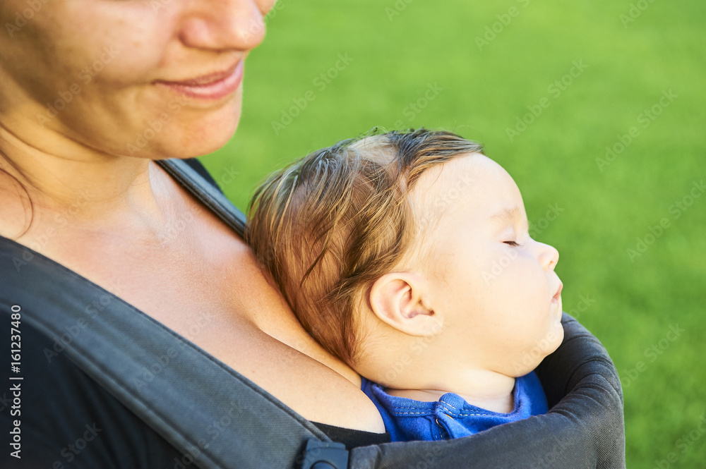 Young mother with her little baby child girl in a carrier outside in nature. Young mother with her little baby child girl in a carrier outside in nature.