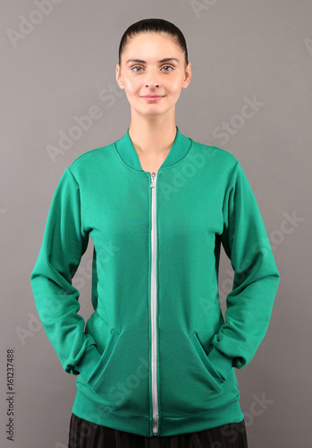 Young hipster girl wearing blank green lime cotton zip up sweatshirt with copy space for your design or logo, mock-up of ltemplate womens hoodie, grey wall in the background photo