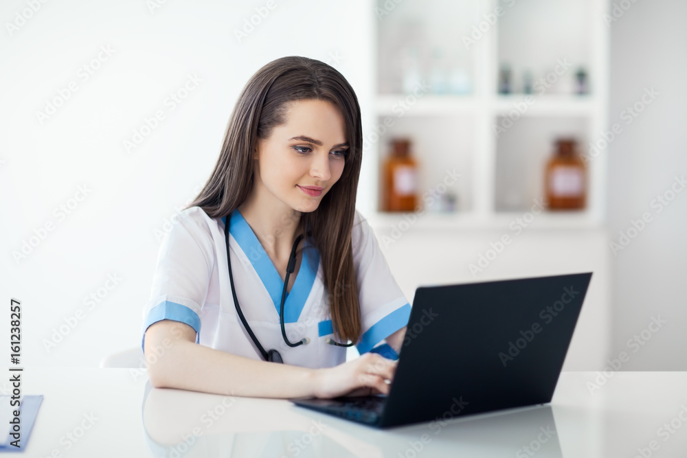 Beautiful doctor working on laptop in hospital Beautiful doctor working on laptop in hospital