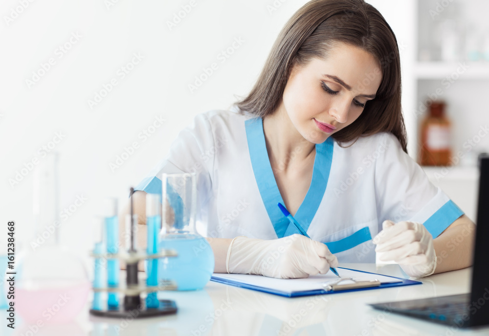Portrait of beautiful female scientist writing notes Portrait of beautiful female scientist writing notes