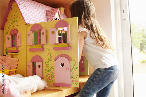 Girl playing with dollhouse in bedroom photo