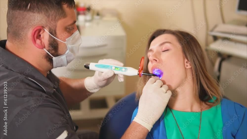 Dentist using ultraviolet lamp on patients teeth. Dental procedure scene Dentist using ultraviolet lamp on patients teeth. Dental procedure scene