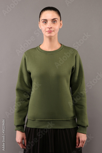 Young hipster girl wearing blank Khaki cotton sweatshirt with copy space for your design or logo, mock-up of ltemplate womens hoodie, grey wall in the background photo