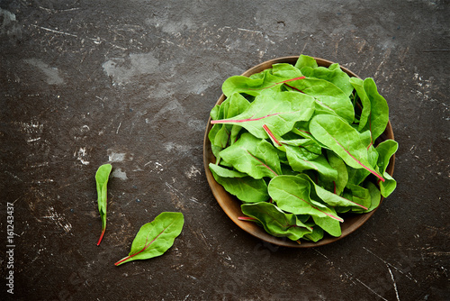 Fresh swiss chard leaves (or mangold) in bowl on brown background

