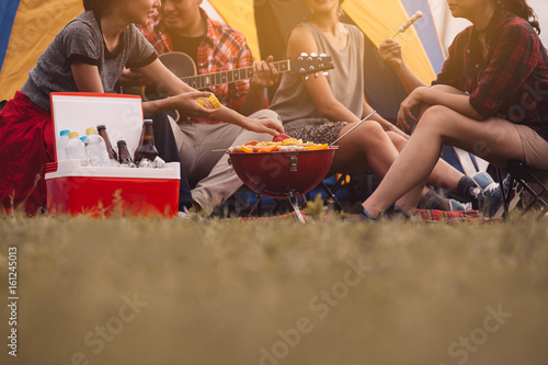 Cropped image of man and woman sitting in chairs outside the tent.Dinner party, Camping barbecue and roast pork ,vintage style ,Relaxation Fun Concept.