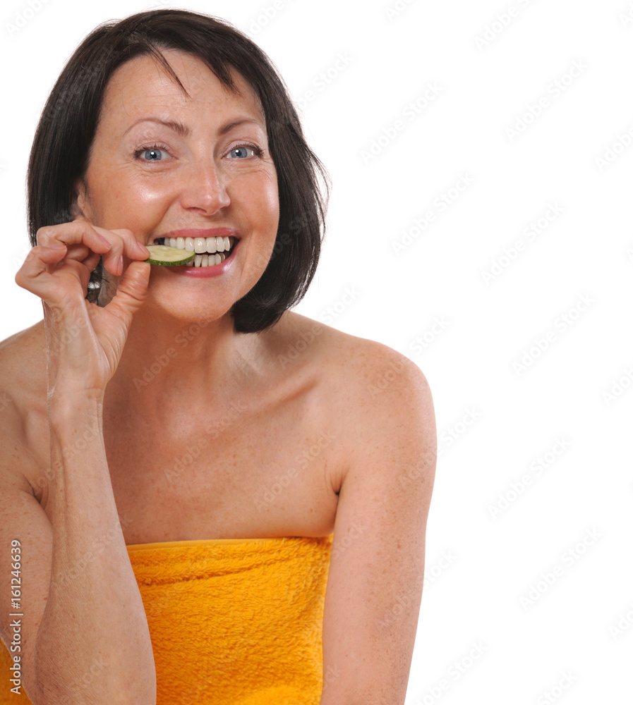 Happy senior woman in spa towel eating piece of cucumber Happy senior woman in spa towel eating piece of cucumber