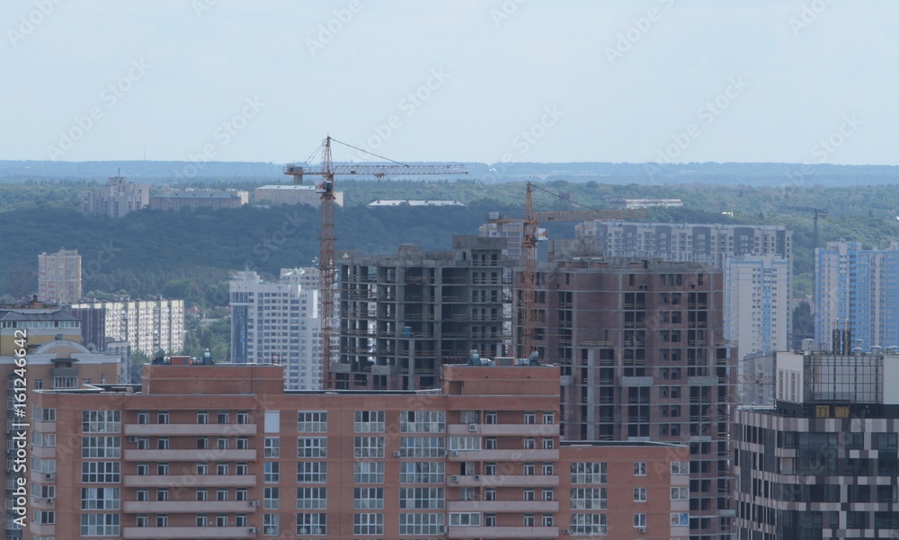 Fototapeta premium Building crane and building under construction against blue sky