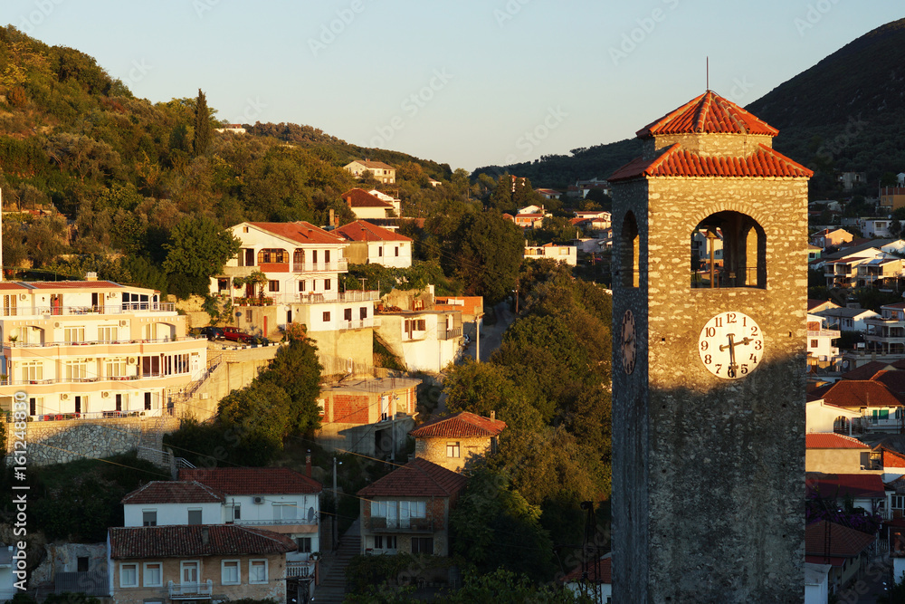 Obraz premium Dawn in a small town, the sun illuminates a stone chapel with a red tiled roof