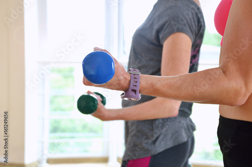 Two aged women do exercises with dumbbells