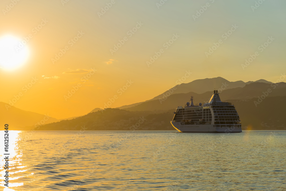 Obraz premium A large liner sails in the rays of the sunset along the Boka-Kotorska Bay. Montenegro.