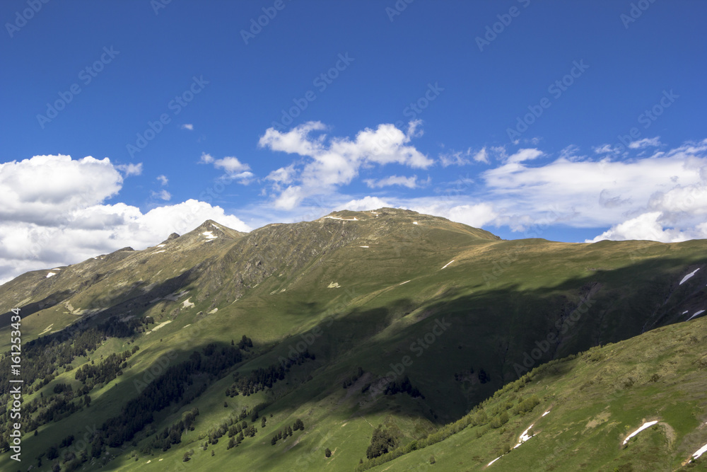 Obraz premium Горный пейзаж, красивый вид на живописные горные склоны, панорама горного ущелья, белые облака на небе, дикая природа и горы Северного Кавказа