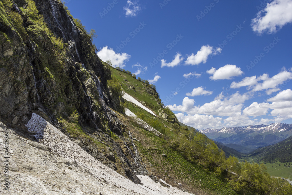 Горный пейзаж, красивый вид на живописные горные склоны, панорама горного ущелья, белые облака на небе, дикая природа и горы Северного Кавказа