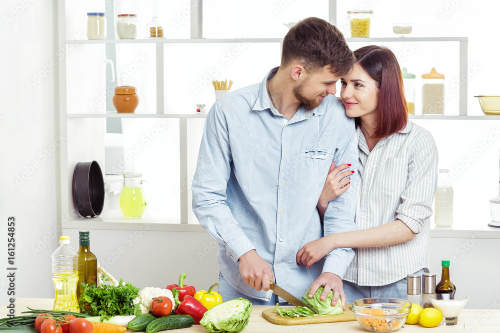 Loving happy couple preparing healthy salad of fresh vegetables in  kitchen