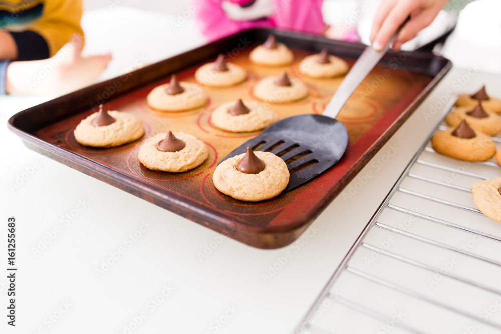 Child moving freshly baked cookies onto cooling rack, mid section, close-up Child moving freshly baked cookies onto cooling rack, mid section, close-up
