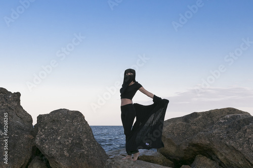 Photos Oriental beauty in a veil on the background of the sea and the moon,symbols of t