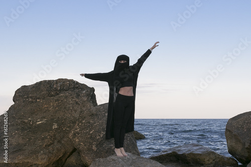 Oriental beauty in a veil on the background of the sea and the moon,symbols of the east