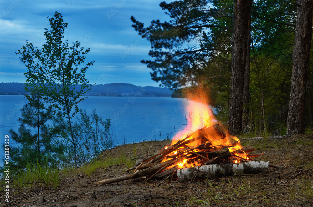 Big night bonfire on the riverbank in the forest clearing, flames, sparks and fireplace. Big night bonfire on the riverbank in the forest clearing, flames, sparks and fireplace.