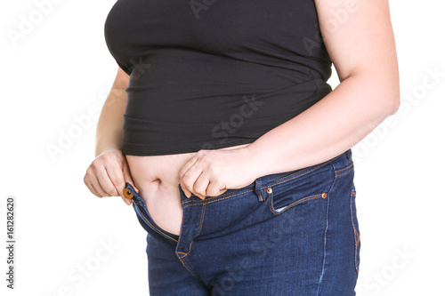 Stout adult woman trying to put on tight jeans against white background. Weight loss concept