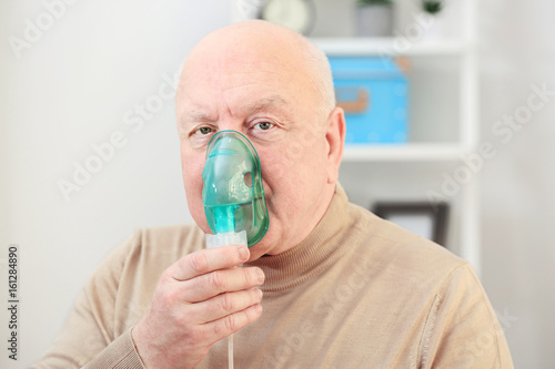 Senior man using asthma machine at home