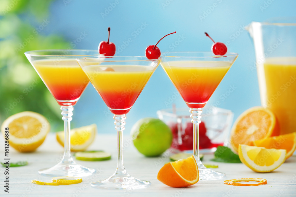 Glasses of Tequila Sunrise cocktail with citrus slices on wooden table