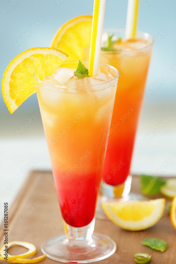 Glasses of Tequila Sunrise cocktail with citrus slices on wooden table Glasses of Tequila Sunrise cocktail with citrus slices on wooden table