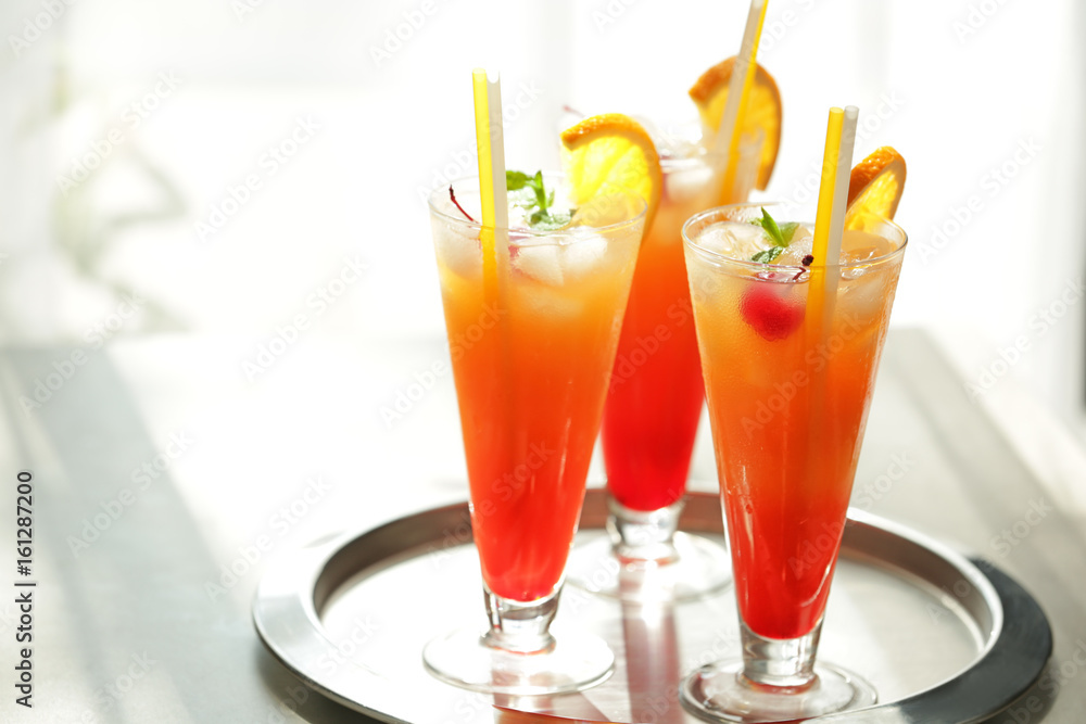 Glasses of Tequila Sunrise cocktail on metallic tray