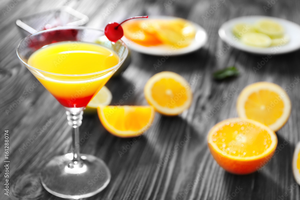 Fototapeta premium Glass of Tequila Sunrise cocktail with orange slices on wooden table