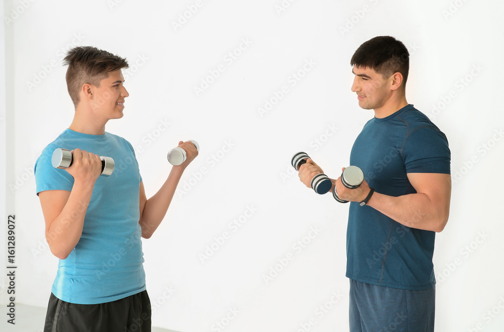 Dad and son training with dumbbells in gym Dad and son training with dumbbells in gym