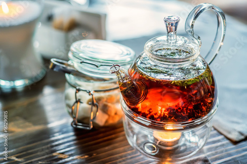 Modern glassy teapot with fresh tea photo