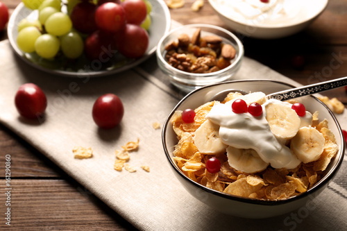 Delicious muesli with banana slices, berries and yogurt on table