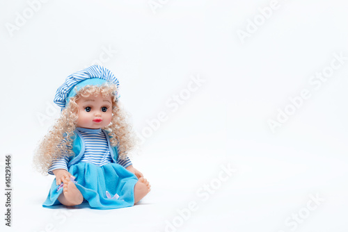 Blond baby doll in blue and white striped dress and hat on white background