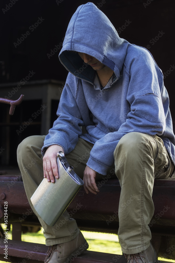 Homeless man sitting and holding a flask Homeless man sitting and holding a flask