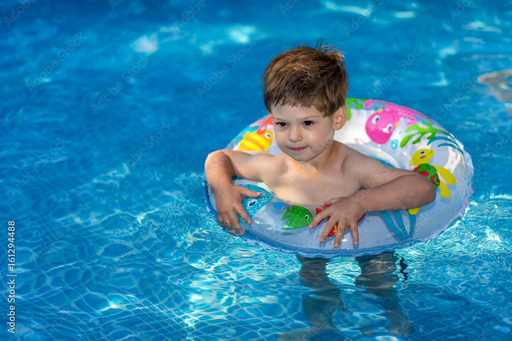 young boy playing in swimming pool wirh float ring