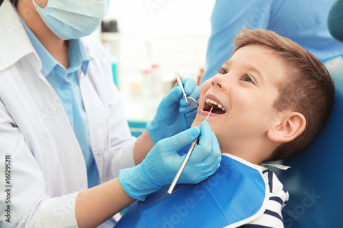 Dentist examining little boy s teeth in clinic