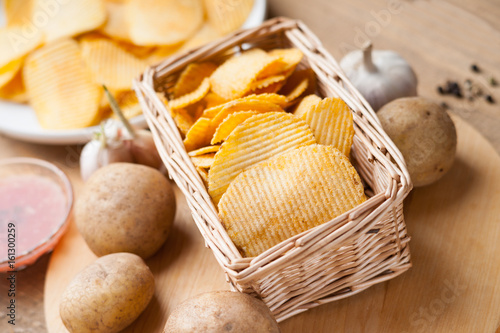 Potato chips in wicker basket and on white dish 