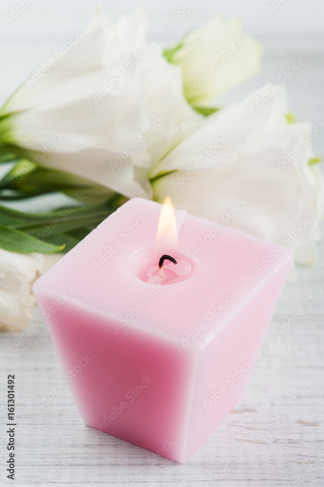 Arrangement of white eustoma flowers and pink lit candle