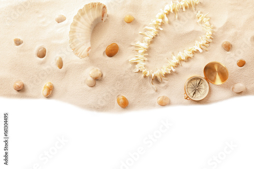 Composition with sand, coral necklace and compass on white background. Concept of travel and vacation